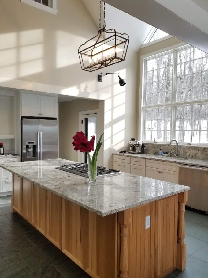 Kitchen island with granite countertop, hickory cabinetry, and cathedral windows — designed by Lacillade Kitchen + Bath