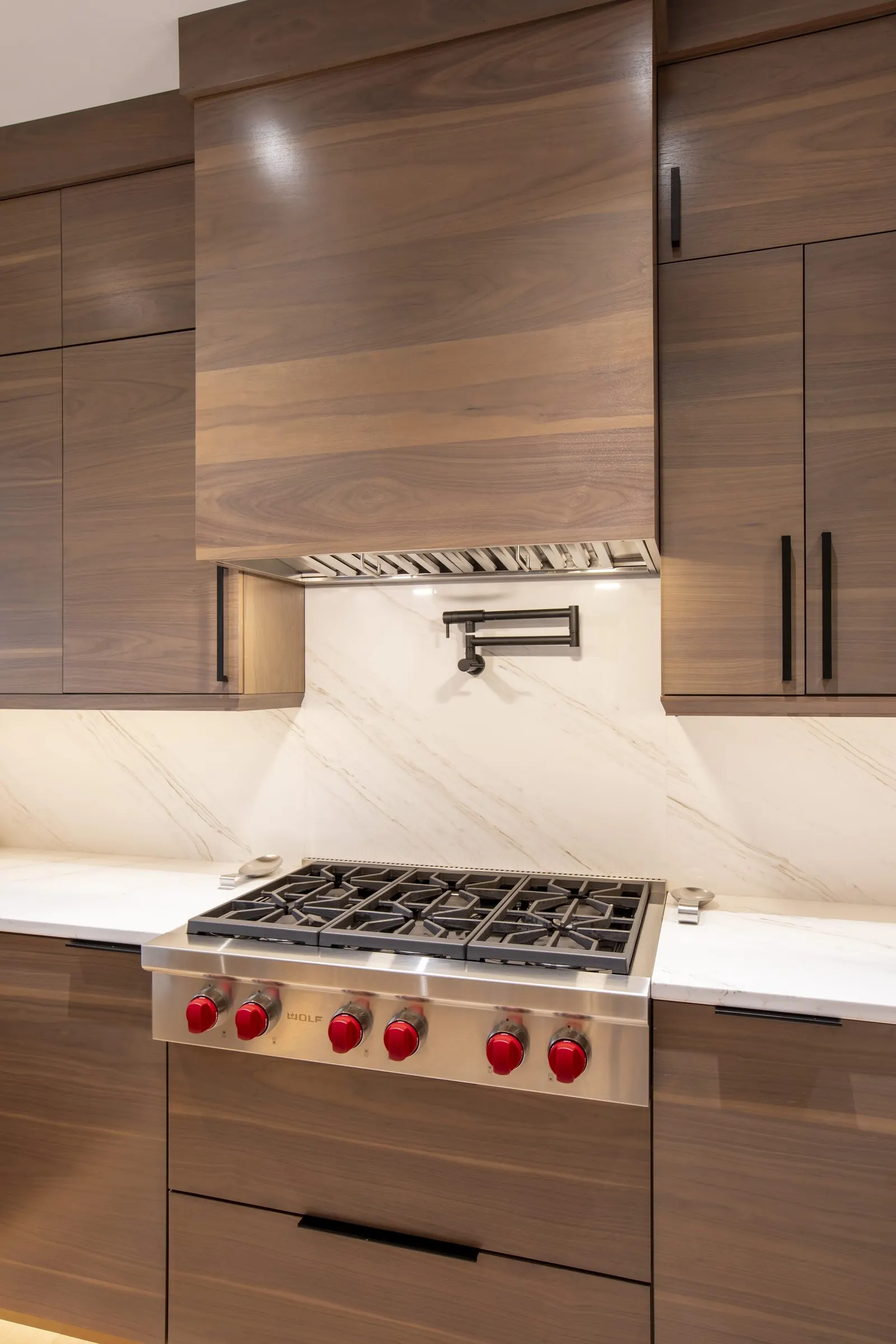 Walnut kitchen cabinetry with a Wolf range, a project designed at the Lacillade showroom in Williston, Vermont