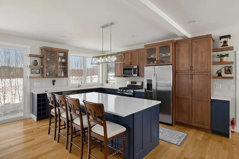 Navy island, wood uppers, and stainless appliances in a snow-view kitchen