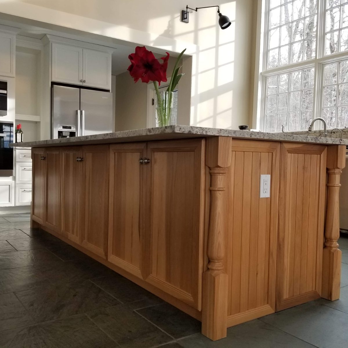 Hickory beadboard kitchen island with turned legs and granite countertop on slate floor